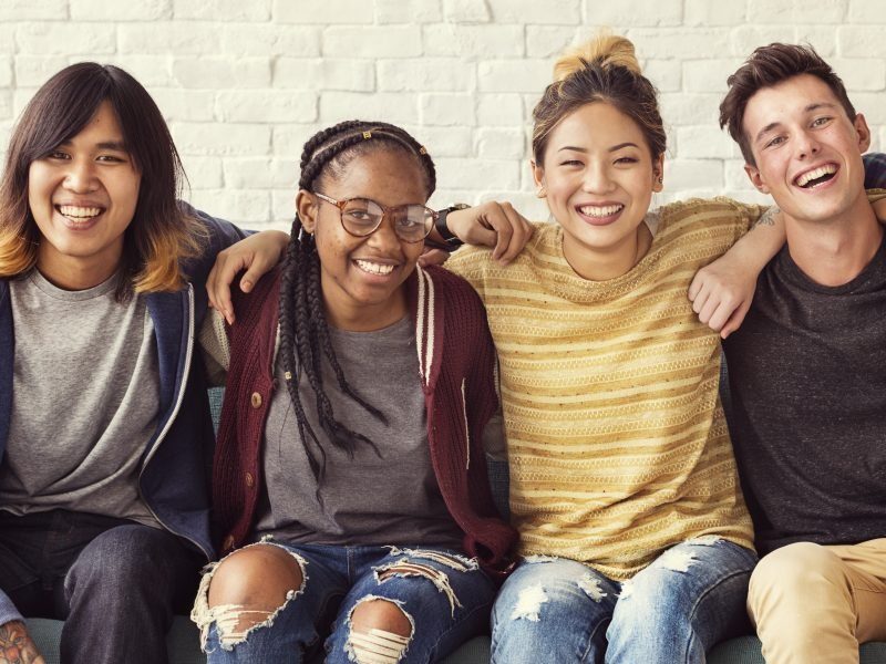 Photo of young adults sitting with hands on shoulders.