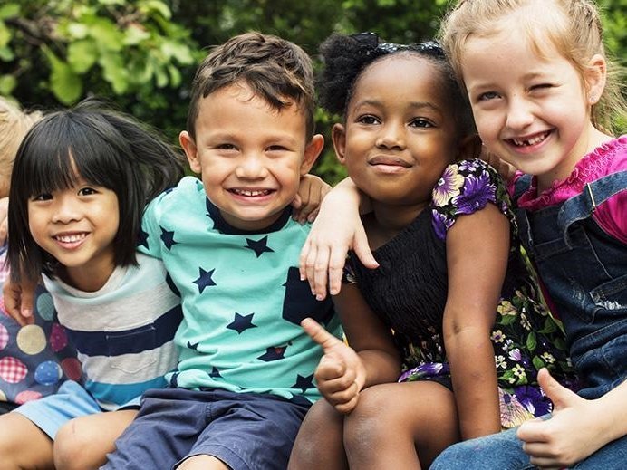 Photo of kids in a row with arms draped around each others shoulder in friendship.